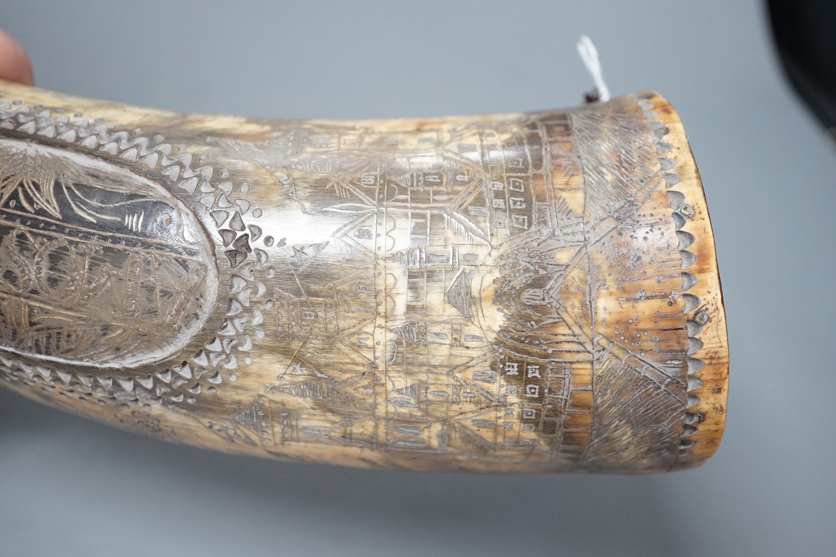 An early 19th century scrimshaw powder horn, ornately engraved with the Royal Coat of Arms, a castle and galleon and an inscription: Amos Mills. 38cms long.